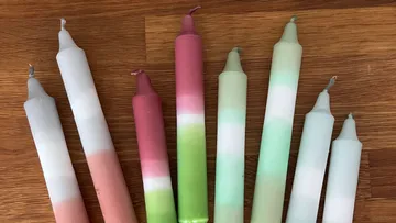 Bunte Kerzen stehen auf einem Holzuntergrund.
