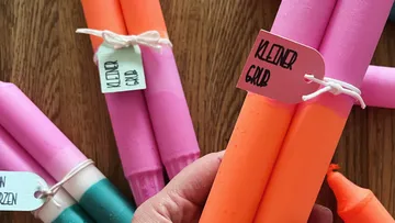 Colourful candles are held in the hand, labelled.