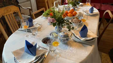 Tisch gedeckt mit Speisen, Getränken und Blumen, festlich.