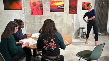 Dancer poses while illustrators work at the table.