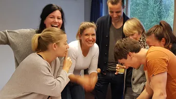 Lachende Menschen interagieren fröhlich in einem Raum.