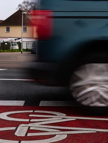 A vehicle quickly crosses a red bicycle lane.