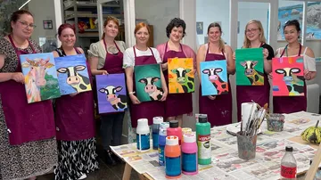 Gruppenausstellung von Frauen mit selbstgemalten Kuhgemälden.