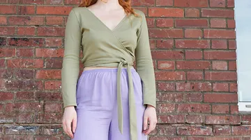 Grüne Bluse mit rosa Hose vor einer Backsteinmauer.
