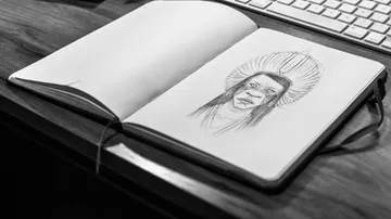 Sketch of a person in an open notebook on a table.