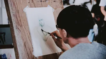 Ein Künstler zeichnet eine Figur auf Papier in einem Atelier.