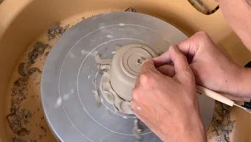 Töpfer benutzt Hände, um eine Drehleihe in einem Studio.