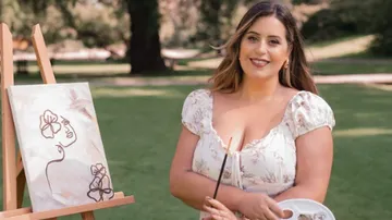 Painting on canvas, the artist poses in the park.