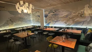 Elegant restaurant with table-set tables and wall art.