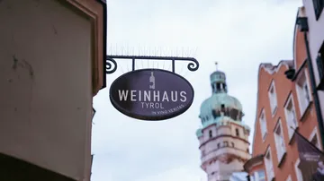 Sign hangs, informs about Weinhaus in Tirol, city center.
