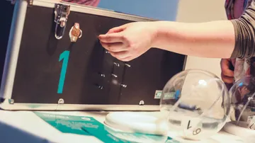 Eine Hand greift in eine Box während einer Veranstaltung.
