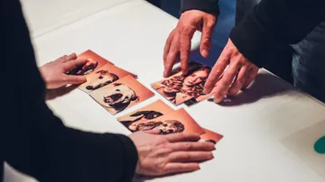 Hände sortieren Fotos auf einem Tisch. Hunde und Menschenbilder.
