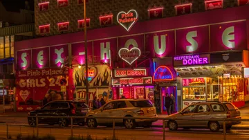 Bunte Fassade eines Erotikhauses mit Neonlichtern, Autos parken.