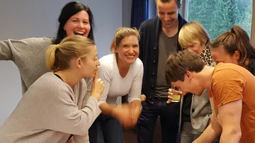 Group of people laugh and interact in a room.