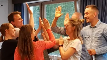 Several people clap their hands, smile happily together.