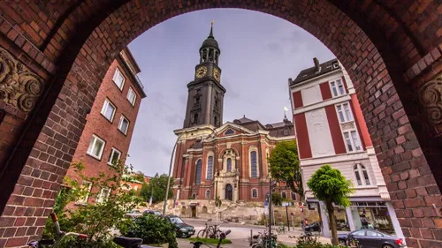 Church with tower stands in front of a city view.