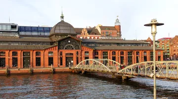 Historisches Gebäude am Wasser, Brücke verbindet zwei Ufer.