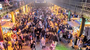 Menschenmenge bewegt sich in einem beleuchteten, festlichen Markt.