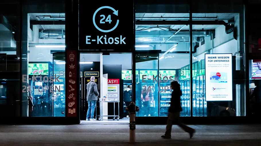 E-kiosk sells snacks; illuminated at night in an urban environment.