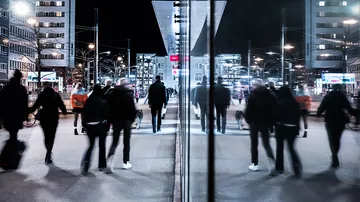 People walk on an illuminated street at night.