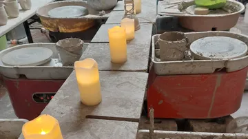 Töpferwerkstatt mit brennenden Kerzen und Werkzeugen.