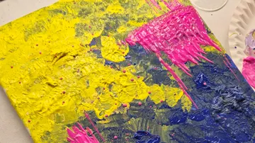 Bunte Farben verlaufen auf einer Leinwand, kreative Maltechniken.