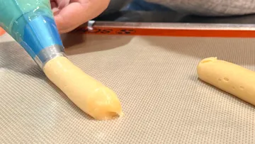 The baking syringe dispenses dough onto a baking tray in the kitchen.