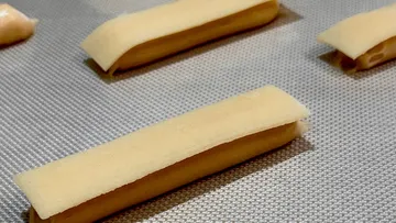 Pieces of dough lie on a baking sheet for baking.