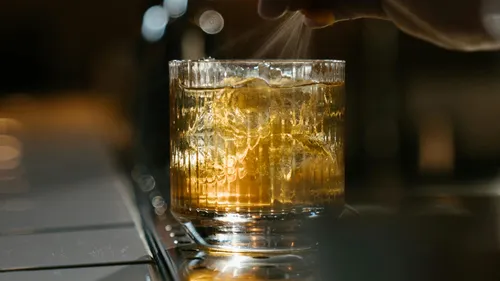 Ein Glas mit Eis wird mit einem Gewürz bestreut.