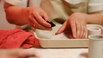 Hands clean dishes in an area covered with cloths.