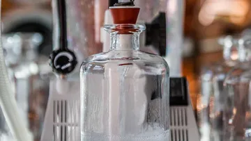 Glass cup with a cap filled with a clear liquid.