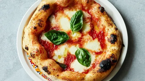 Pizza mit Tomatensauce, Mozzarella und frischem Basilikum serviert.