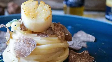 Pasta mit einer Jakobsmuschel, umgeben von Trüffeln.