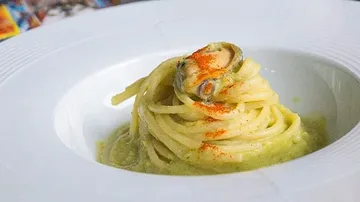 Spaghetti auf Püree, mit Muschel und Paprika bestreut.