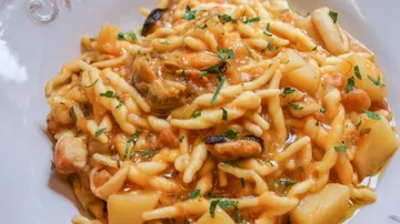 Spaghetti with sauce and herbs on white plate.
