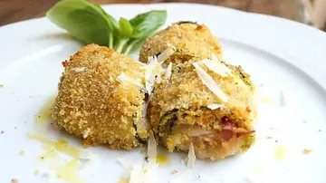 Breaded zucchini rolls are laid out on a white plate.