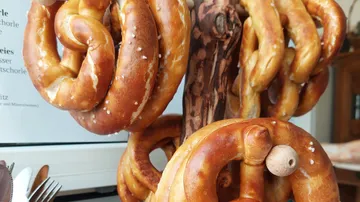 Brezeln hängen an einem Holzständer in einem Raum.