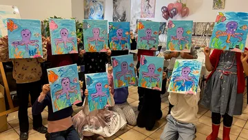 Kinder halten Bilder von einem Oktopus in einem Raum.