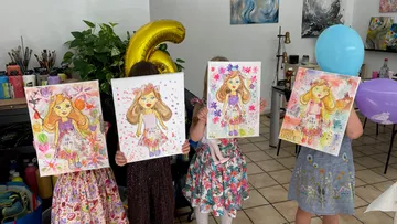 Vier Mädchen zeigen ihre Kunstwerke in einem Raum.