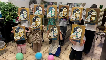 Children keep paintings of owls in a room.