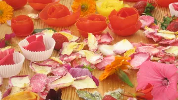 Bunte Blüten und Stücke liegen auf einem Holztisch.