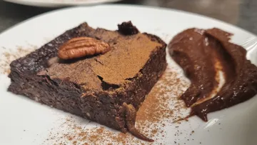 Schokoladenkuchenstück mit Nuss und Schokoladensoße auf Teller.