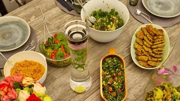 Table set with various salads and drinks.