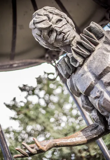 Eine Statue mit nach oben gestrecktem Arm im Park.