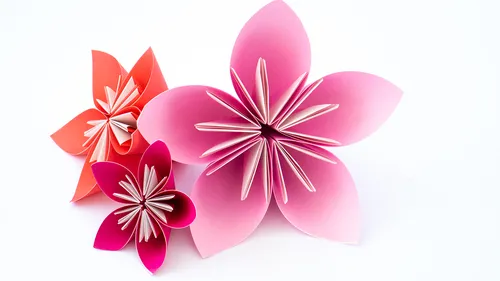 Paper flowers of various colors stand on a white background.