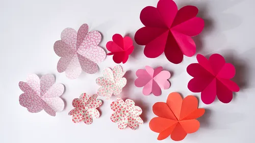Colourful paper flowers are spread over a white background.
