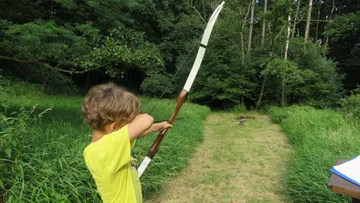 A boy aims at a target with a bow.