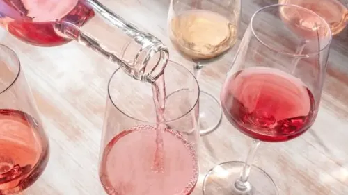 Ein Glas wird mit Roséwein gefüllt, umgeben von weiteren Gläsern.
