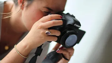 Frau fotografiert mit einer Kamera in hellem Raum.