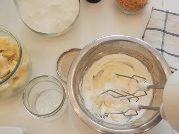 Bowl of whipped cream surrounded by ingredients and accessories.